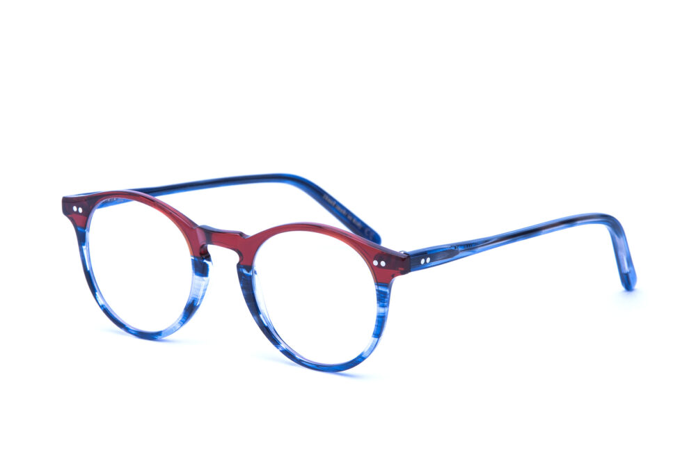 Adamo è un occhiale da vista in acetato bicolore, con una forma tondeggiante e un ponte a forma di buco della serratura realizzata con maestria artigianale