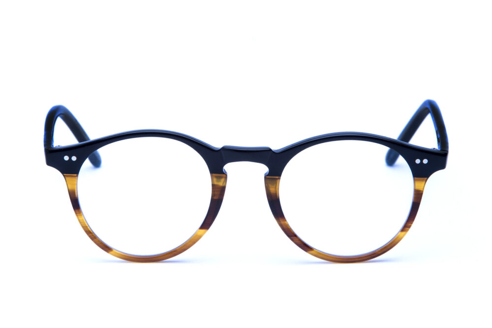 Adamo è un occhiale da vista in acetato bicolore, con una forma tondeggiante e un ponte a forma di buco della serratura realizzata con maestria artigianale