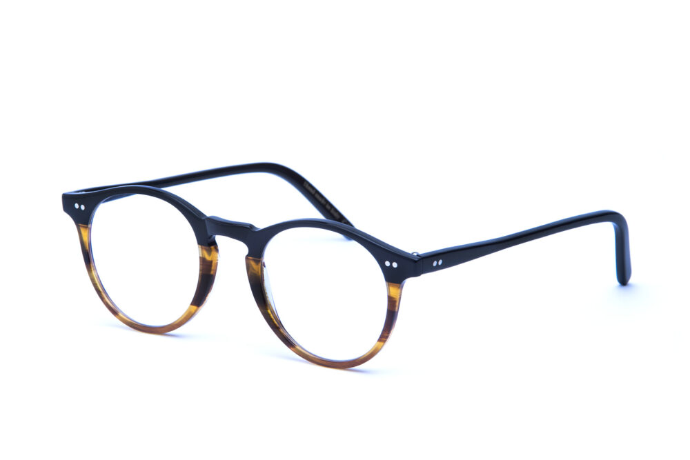 Adamo è un occhiale da vista in acetato bicolore, con una forma tondeggiante e un ponte a forma di buco della serratura realizzata con maestria artigianale
